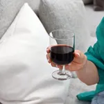 Hosteria Goblet 345ml in use, held in a hand with red wine, showing the short stem and circular base of the clear glass.