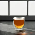 Close-up of a Brew Infusion Double Wall Glass 220ml tumbler filled with amber liquid, highlighting the clear gap between the inner and outer walls.