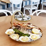 Chef Inox Round Seafood Stand 2-Tier Brass in use, holding grilled fish and oysters on ice