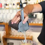 D-Still Hawthorn Strainer in use, dark grey stainless steel with perforated disc and spring coil