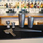 D-Still Hawthorn Strainer 165x100mm in brushed stainless steel, shown flat on a bar mat with shakers