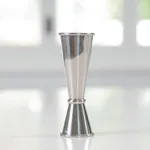 Close-up of the D-Still Jigger 30/60ml Stainless Steel, showing the polished double-cone design and etched markings on the rims.