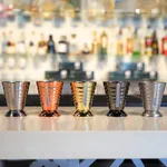 Five D-Still Multi Level Jigger 75ml fluted metal measures in silver, copper, gold, and black finishes lined up in a row.