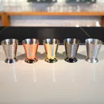 Five D-Still Multi Level Jigger 75ml Black metal jiggers in silver, copper, gold, and black finishes with textured exteriors and engraved markings.