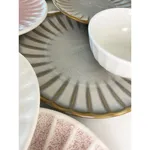 Close-up of the Round Bowl Scallop in matte white porcelain with a grey interior, displayed on a ridged plate with other Moda Porcelain pieces.