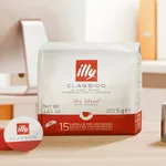 Illy Cafe MPS Decaf capsules close-up showing the white and red Classico pouch and a single capsule on a wooden surface