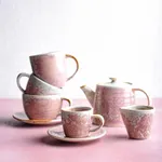 Moda Porcelain Icon Coffee / Tea Cup set in a lifestyle scene, showing stacked and individual cups with a mottled pink glaze and gold rims.