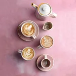 Moda Porcelain Icon Coffee / Tea Cup set in use, featuring speckled white and pink glazed cups with latte art and a matching teapot.