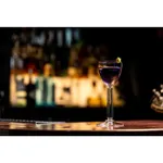Libbey Modern America Nick & Nora glass in use with a purple drink and citrus twist on a wooden bar