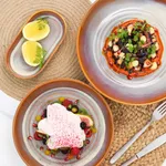Urban Loft Auburn Serve Platter in use with roasted vegetables, pomegranate, and herbs on a jute mat