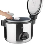 Apuro Jumbo Rice Cooker in use, showing a hand scooping cooked rice from the open stainless steel pot with black handles.