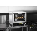 Apuro convection oven in use on a worktop, showing the open door, bread on a rack, and black control panel with yellow logo.