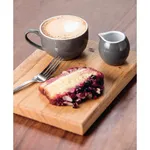 Olympia Cafe Cappuccino Cup Charcoal in use with latte art, creamer jug, and cake on a wooden board