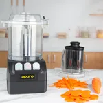 Apuro Multi Function Food Processor in use on a marble counter, showing the black base, clear bowl, and a stainless-steel juicer attachment next to shredded carrots.