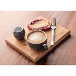 Olympia Cafe Cappuccino Cup Charcoal in use, filled with frothed coffee on a wooden board with a matching jug and cake slice.