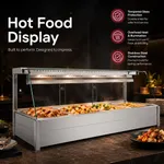 Bonvue BM17TC angled bain marie in use on a marble counter, holding four steaming food pans behind a curved tempered glass shield.