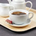 Olympia Athena cappuccino cup in use, filled with coffee on a saucer, featuring a white glossy finish and curved handle.