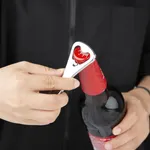 Olympia Crown Bottle Opener in use, close-up of the silver lever and red crown grip opening a red cap on a dark glass bottle.