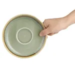 Olympia Kiln Moss Saucer held in hand from above, showing pale sage-green interior and speckled brown rim.