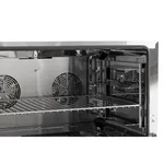 Apuro convection oven interior close-up showing polished stainless steel cavity, wire rack shelf, and circular fan grilles on the back wall