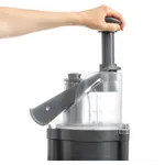Dito Sama Prep4you Vegetable Slicer in use, showing a hand pressing the black plunger on the clear chamber with a dark grey base.