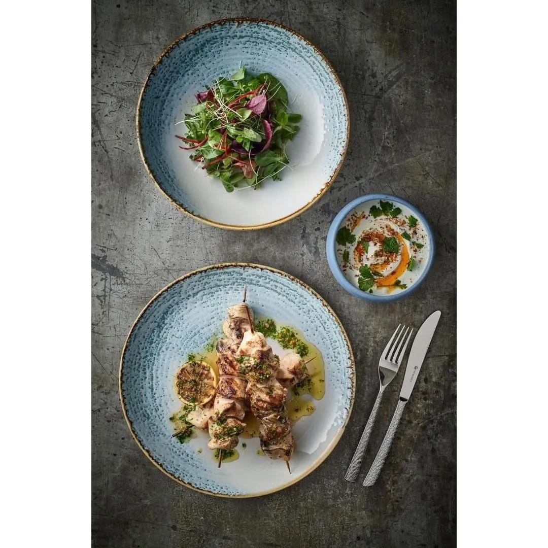Churchill Round Plate-Coupe, 217mm, in use with a skewered meat dish, featuring a speckled light blue glaze and textured gold-toned rim.