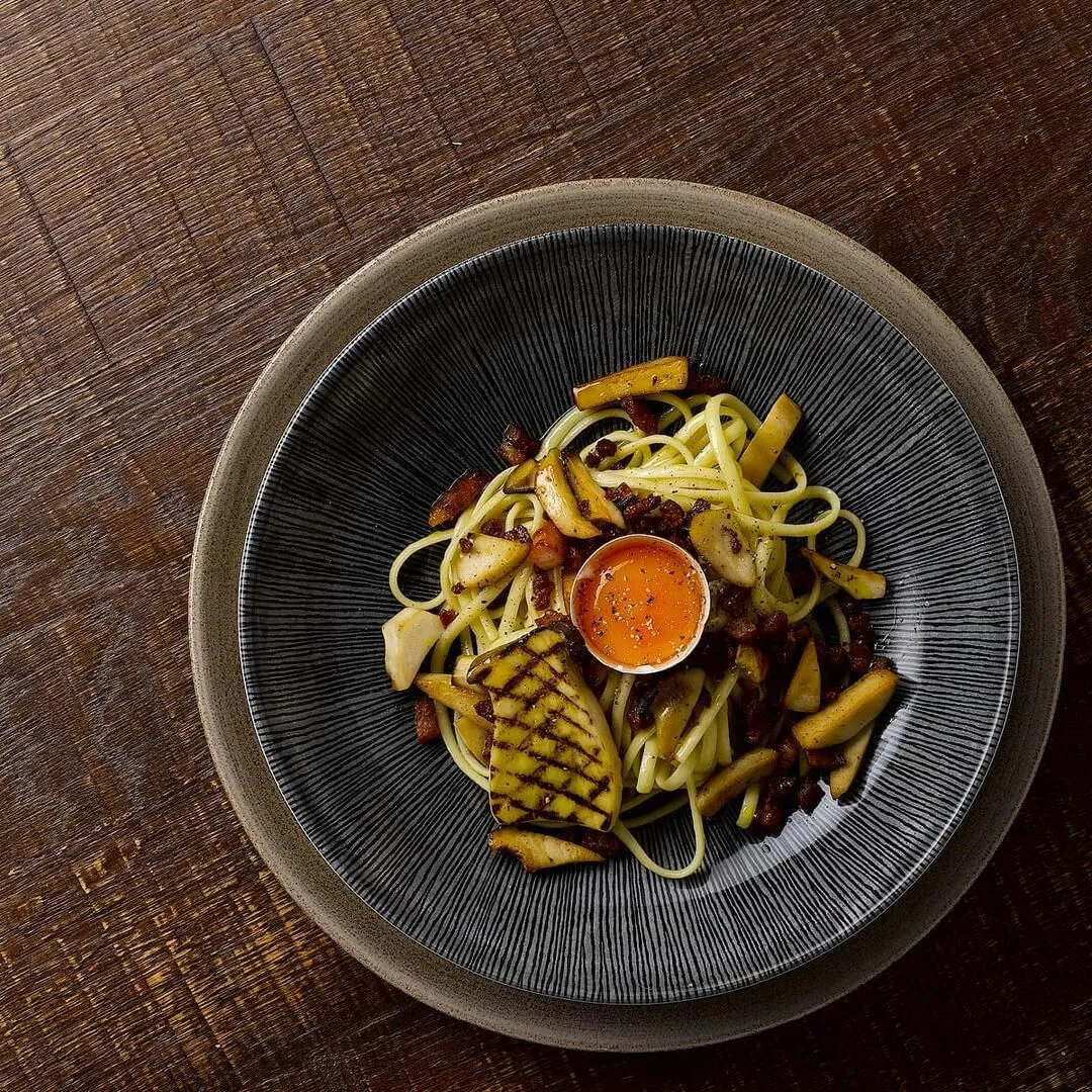 Churchill Round Coupe Bowl in use, overhead view of dark grey ribbed interior holding a pasta dish with grilled squid and orange sauce.