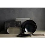 Dudson Round Coupe Bowl in speckled grey stoneware, shown in a lifestyle scene with matching plates and a slate board.