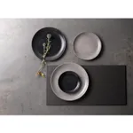 Dudson Round Coupe Plate in speckled matte ceramic, shown in a top-down lifestyle scene with three plates on a concrete surface.