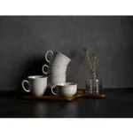 Five matte white ceramic teacups with ribbed texture and C-shaped handles arranged on a dark wooden tray