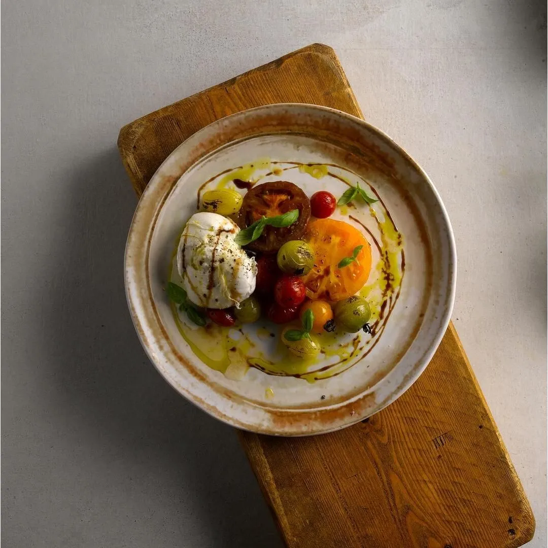 Dudson Organic Coupe Plate in use, overhead view of the cream glaze and mottled brown rim holding a poached egg dish.
