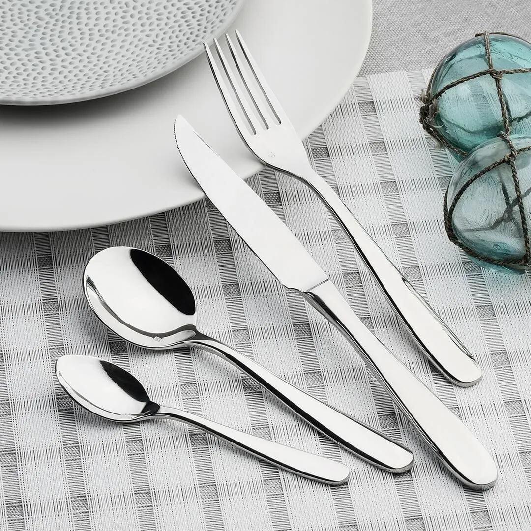 Fortessa Grand City 18/10 stainless steel dessert fork in use on a woven placemat with knife and spoons