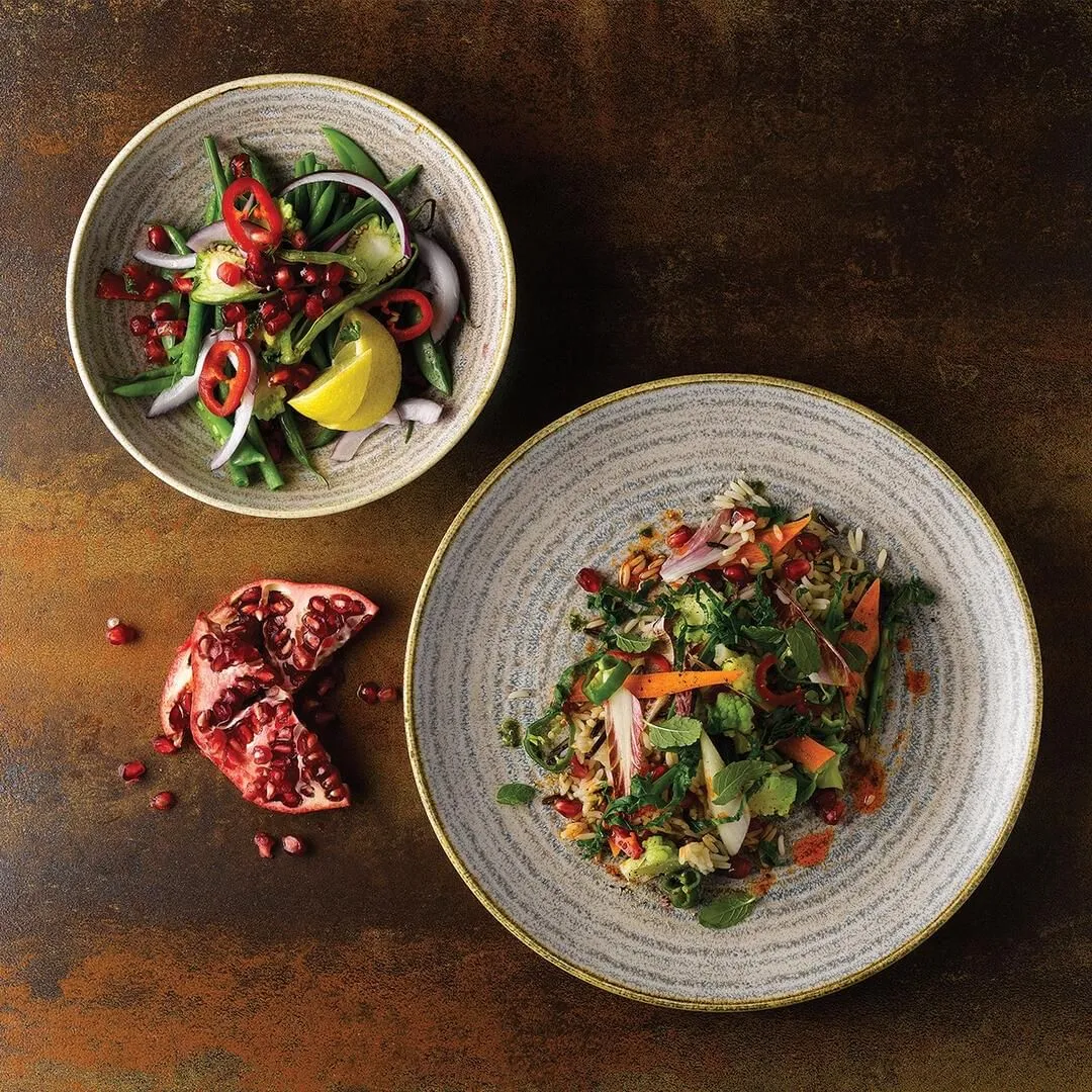 Churchill round coupe plates in speckled grey and white glaze with gold rims, shown in use with mixed salads