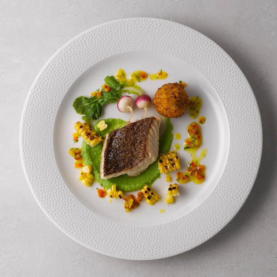 Churchill Round Wide Rim Plate in use, overhead view of white plate with textured rim holding a plated fish dish