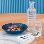 Luzerne rectangular share plate in use, holding a fruit salad in a dark blue textured bowl on a white marble tray.