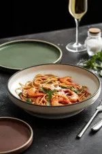Luzerne Dusted White round bowl in use, filled with shrimp pasta to show its wide, shallow profile and dark rimmed edge.