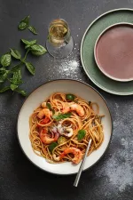 Luzerne Dusted White share bowl in use, overhead view of wide matte white interior with dark grey rim filled with pasta.