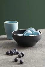 Luzerne Midnight round bowl in use, filled with macarons on a stone surface