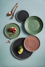 Luzerne Round Stackable Plate in use with food props, showing the speckled midnight black, sage, and rose ceramic finish.