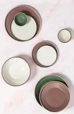 Luzerne Smokey Basil tableware set in overhead flat-lay, featuring speckled mauve and green rims on cream interiors.