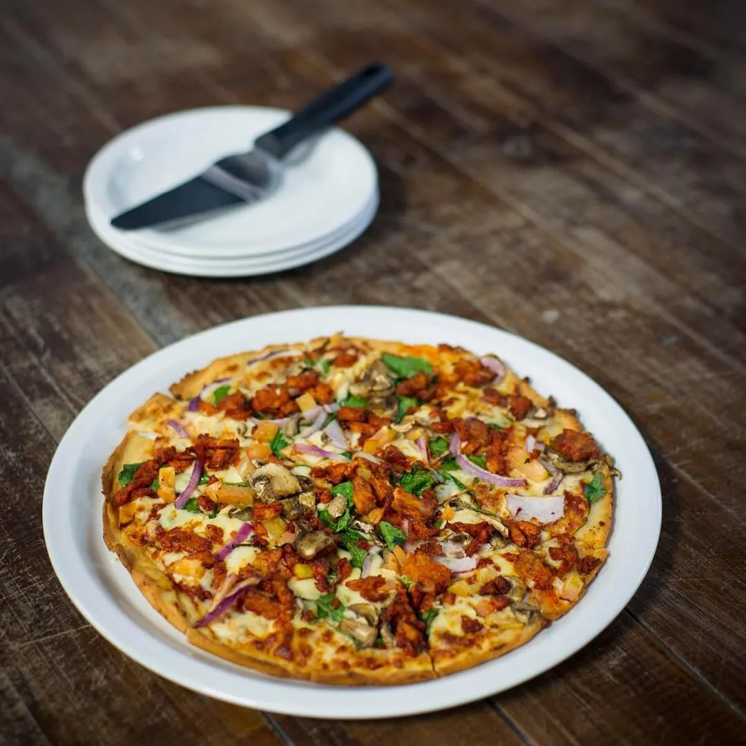 Churchill Round Narrow Rim Plate in use holding a pizza on a dark wooden table