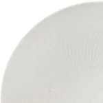Luzerne Round Bowl close-up showing the curved white rim and interior with a fine ribbed texture and dark speckles on the matte surface.
